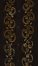 Close-up of a black garment with gold decorative patterns on a dark background